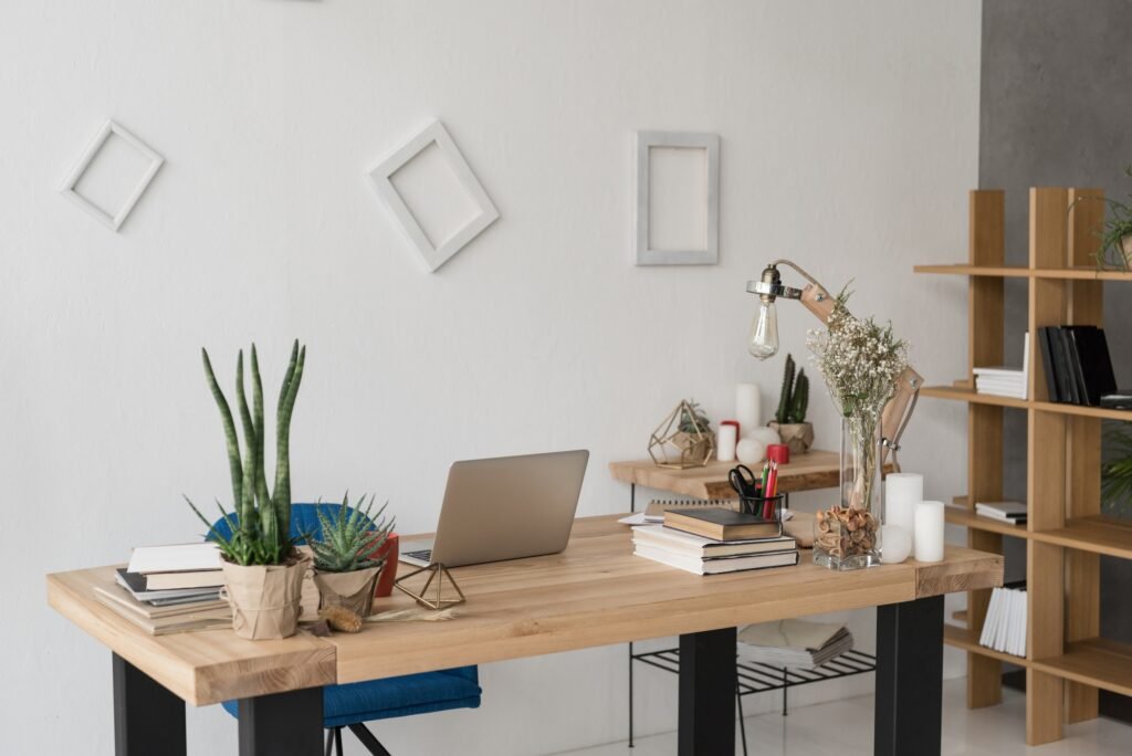 office table with laptop, books, candles and office supplies